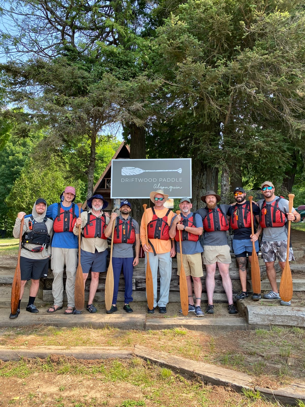 A group of men in life jackets holding canoe paddles
